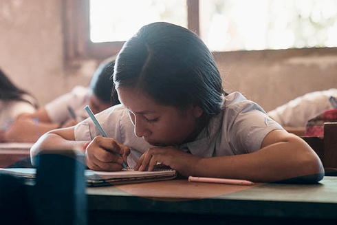 A child writing on a book. IDB