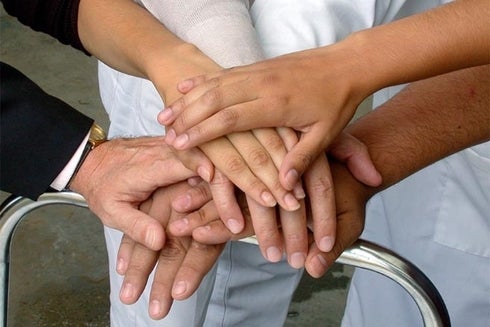 A group of people putting their hands together. Development - Inter-American Development Bank – IDB
