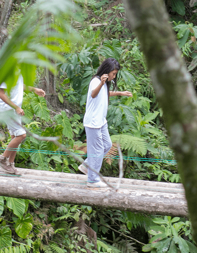 Children crossing an unstable wooden bridge together.