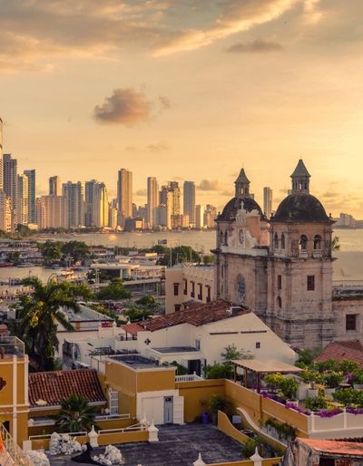 Aerial view of the historic center of Cartagena de Indias, Colombia, with the modern skyline in the background and the sea beyond.