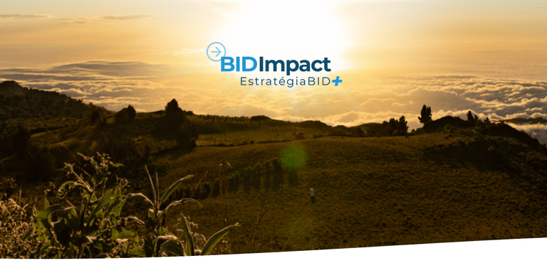Uma vista de uma paisagem ao nascer do sol, com colinas verdes, picos de montanhas distantes e um mar de nuvens sob um céu. A imagem apresenta o logotipo da BID Impact e o texto 'Estratégia BID+.'