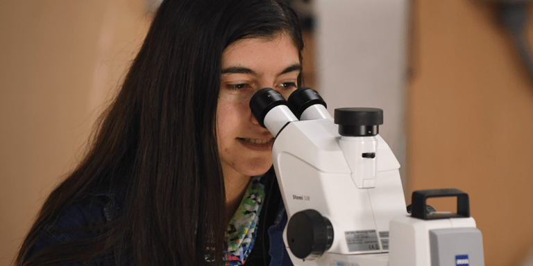 Woman sitting and watching a microscope - Inter American Development Bank - Measuring Results