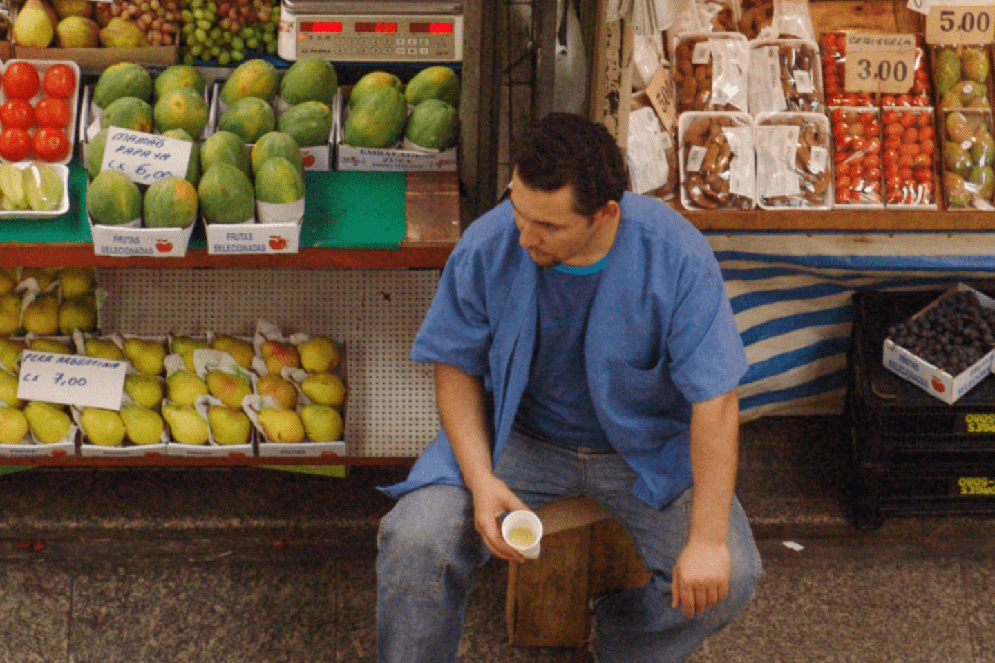 Man standing in front of a fruit stall at a local market in Latin America and the Caribbean
