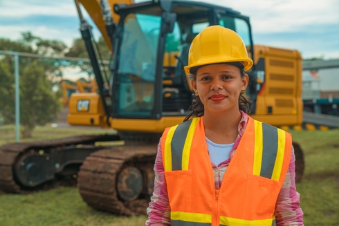 Mujer con equipo de seguridad delante de retroexcavadora. Equidad de género y diversidad - Banco Interamericano de Desarrollo