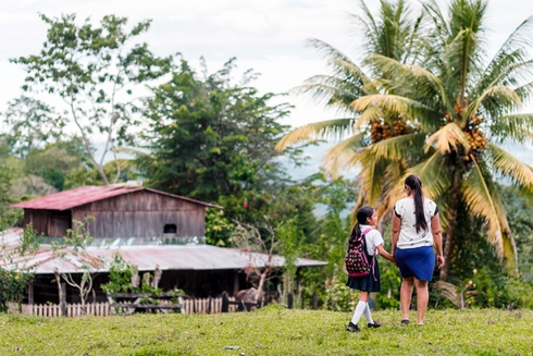 Madre llevando a su hija al colegio en el campo. Desarrollo rural y educación - Banco Interamericano de Desarrollo - BID 