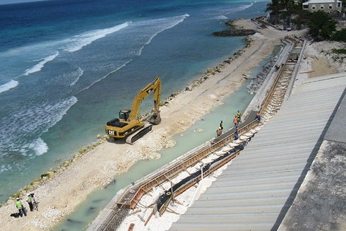 A construction site on the beach with a large yellow excavator. Social Protection - Inter-American Development Bank - IDB