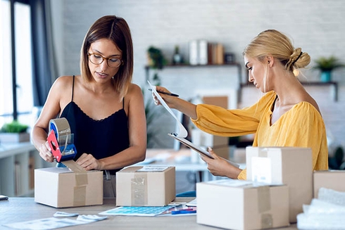 A woman packing boxes next to a woman with a clipboard. Entrepreneurship - Inter-American Development Bank - IDB