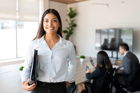 Woman holding a folder and smiling. Social development - Inter-American Development Bank - IDB