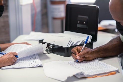 A person writing on papers on a desk