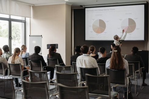 a person standing in front of a screen with a group of people sitting in chairs