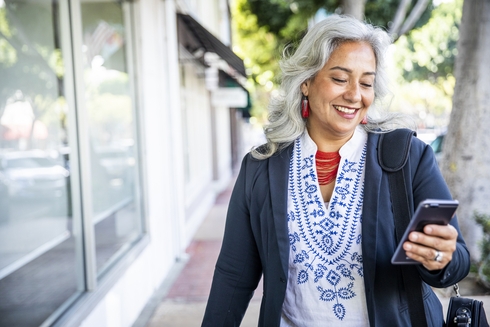 A person smiling while holding a phone. Social development - Inter-American Development Bank - IDB