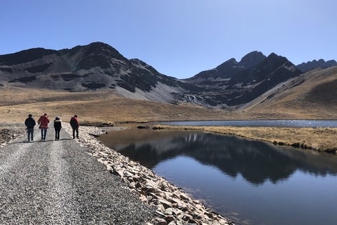 A group of people walking on a rocky path by a lake - Inter-American Development Bank - IDB