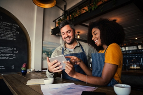 A woman and a man looking at a tablet - Financial Inclusion - Inter-American Development Bank - IDB