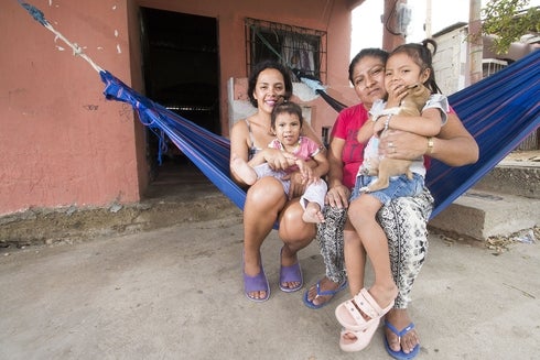 Two women with their children sitting in a hammock smiling - Housing - IDB - Inter-American Development