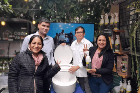 Group of people standing with a toilet - Source of Innovation - Inter American Development Bank - IDB