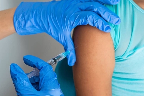A person's arm and hands applying a vaccine - Inter American Development Bank - Research at the IDB