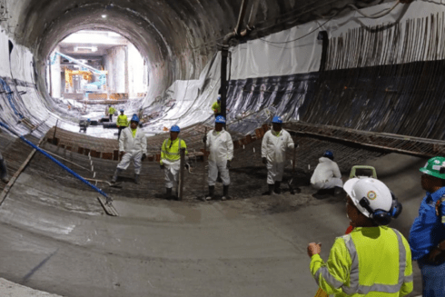 Workers wearing hard hats face-to-face inside a tunnel under construction - Inter American Development Bank - IDB Impact
