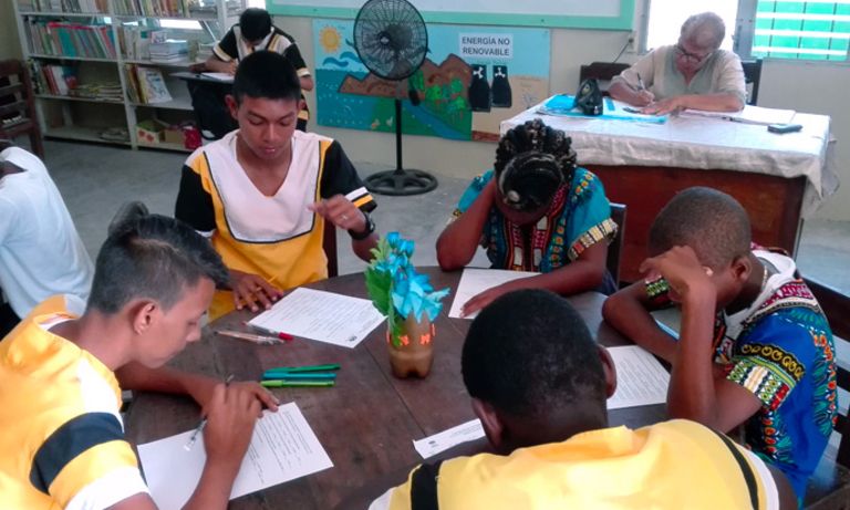 Jóvenes sentados en una mesa redonda estudiando. Educación y equidad de género - Banco Interamericano de Desarrollo - BID