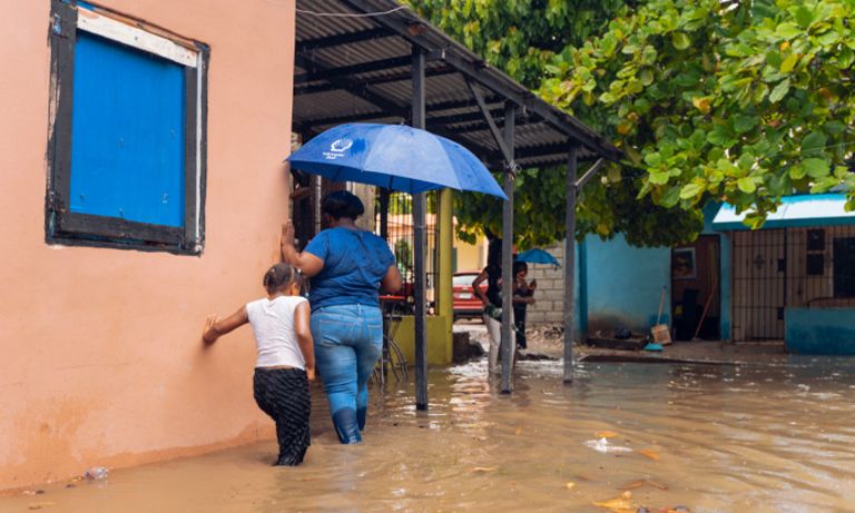 A woman and a child walking through flooded streets. Fiscal policy - Inter-American Development Bank - IDB
