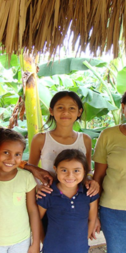 Familia sonriendo de pie al lado de su casa. Desarrollo rural y económico - Banco Interamericano de Desarrollo - BID 