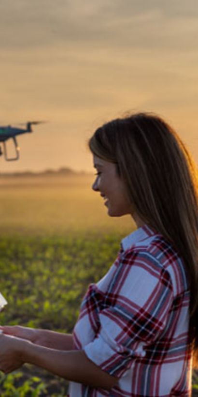 A woman holding a drone in a field. Employment - Inter-American Development Bank - IDB